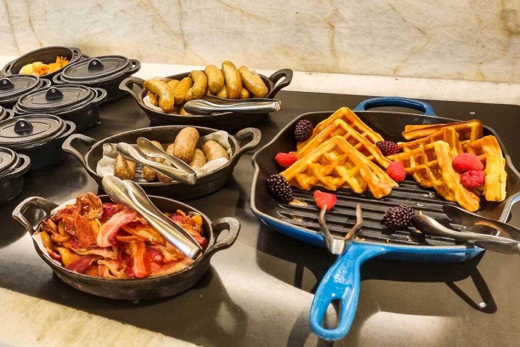 Amerikanisches Frühstück mit Bacon, Würstchen, Waffeln